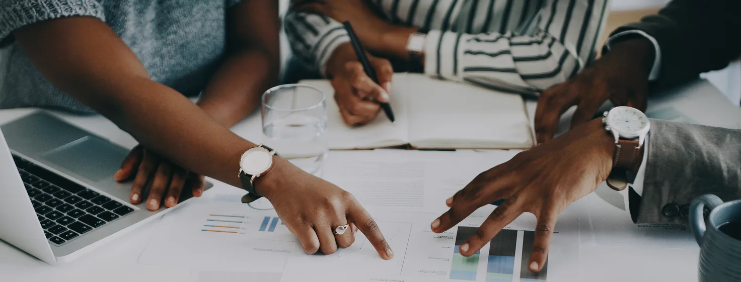 Closeup shot of a group of unrecognisable businesspeople analysing graphs in an office