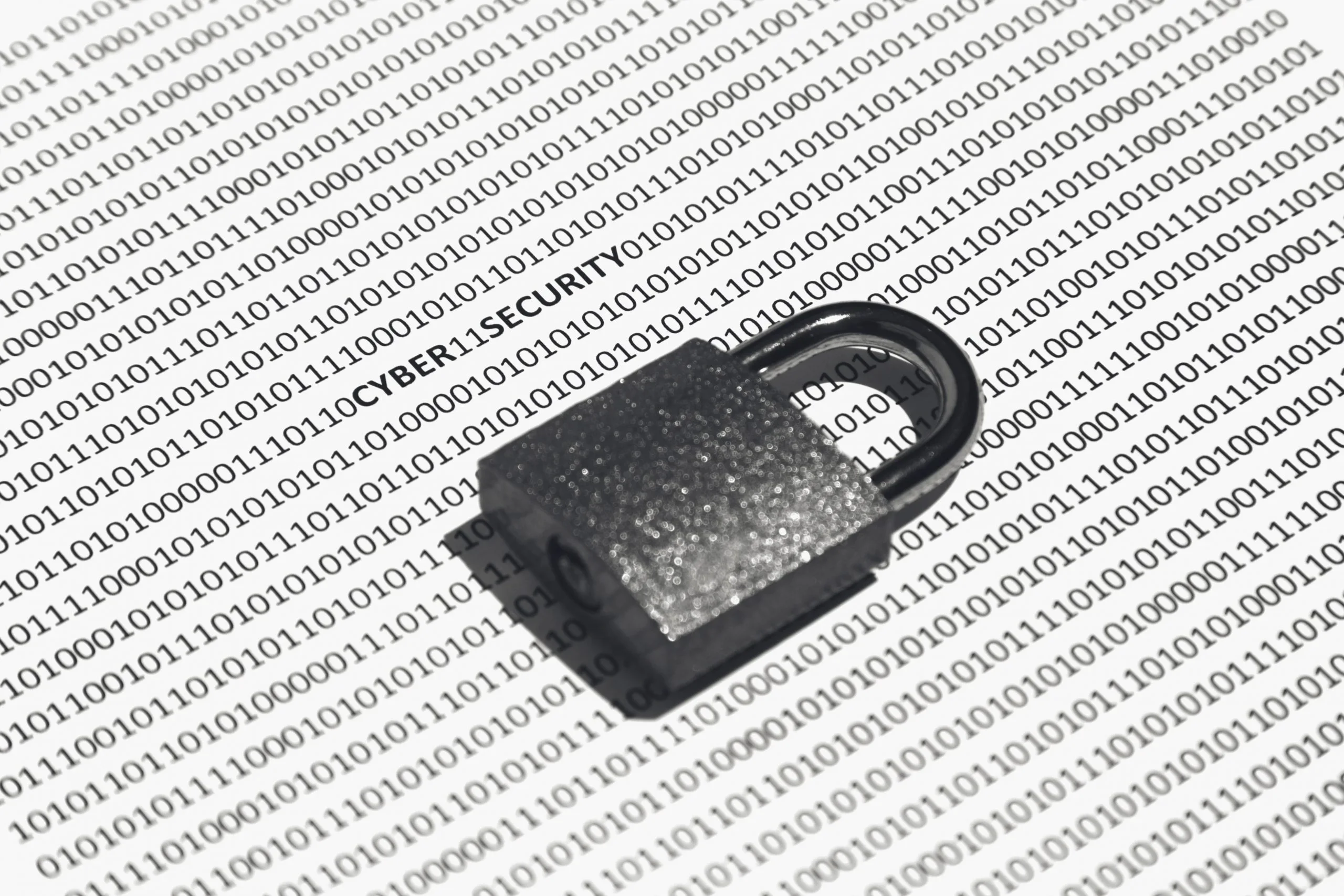 A closeup shot of a lock on a white surface with cyber security, ones, and zeros written on it