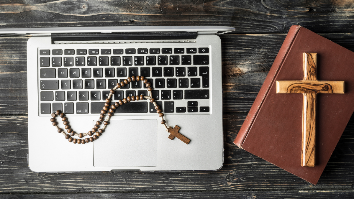 Um terço sobre o teclado de um notebook e um crucifixo em cima de um livro - Startups