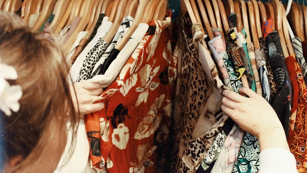 Uma mulher olhando várias roupas estampadas - Startups