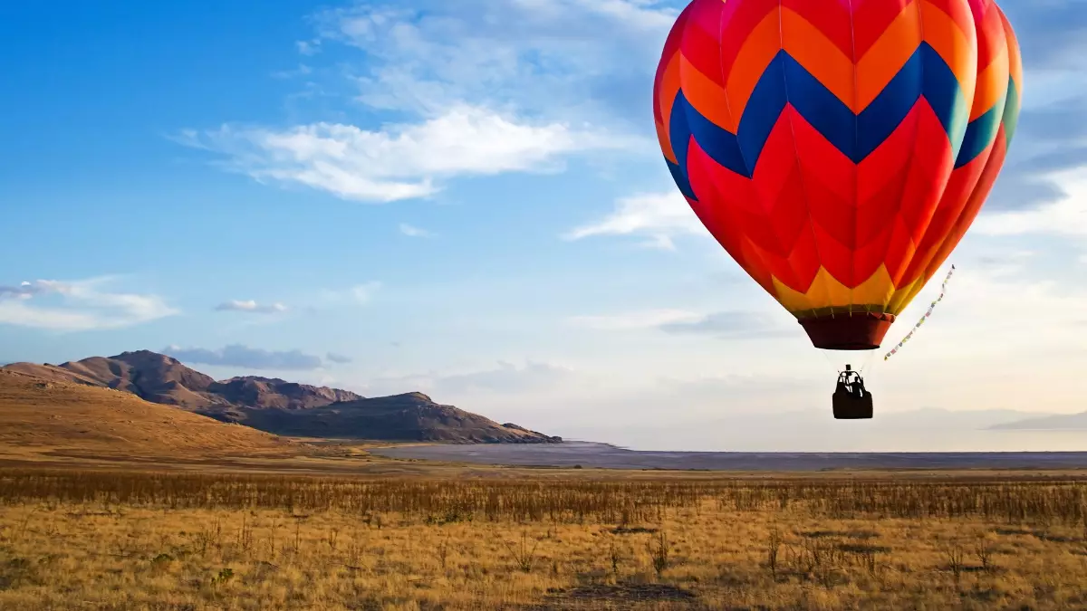 Um balão laranja no ar, no horizonte o céu com nuvens e montanhas - Startups