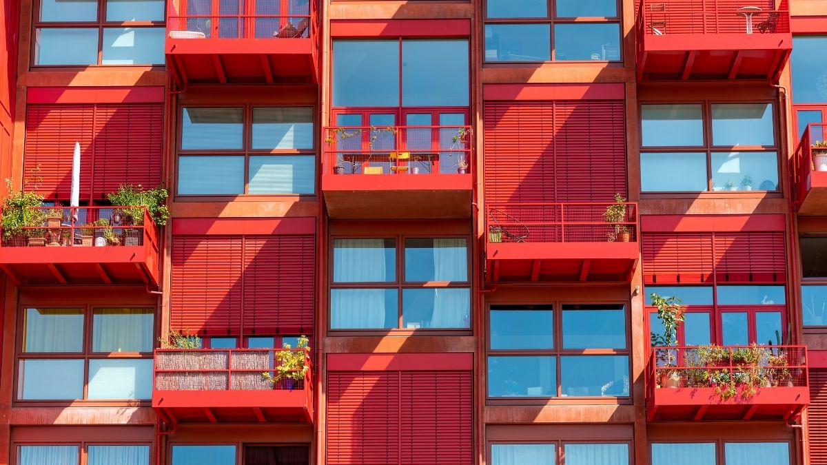 Várias sacadas e janelas de apartamentos de um edifício vermelho - Startups