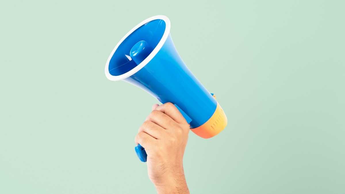 Uma mão segurando um megafone azul - Startups
