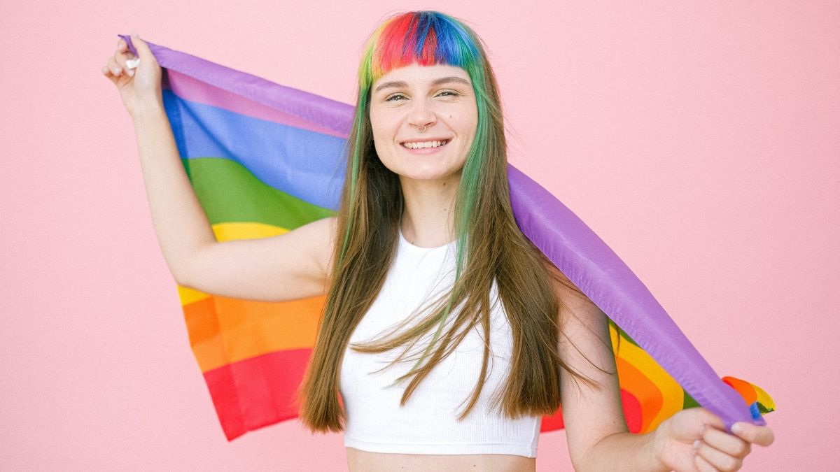 Mulher com o cabelo colorido e segurando uma bandeira LGBTQIA+ - Startups
