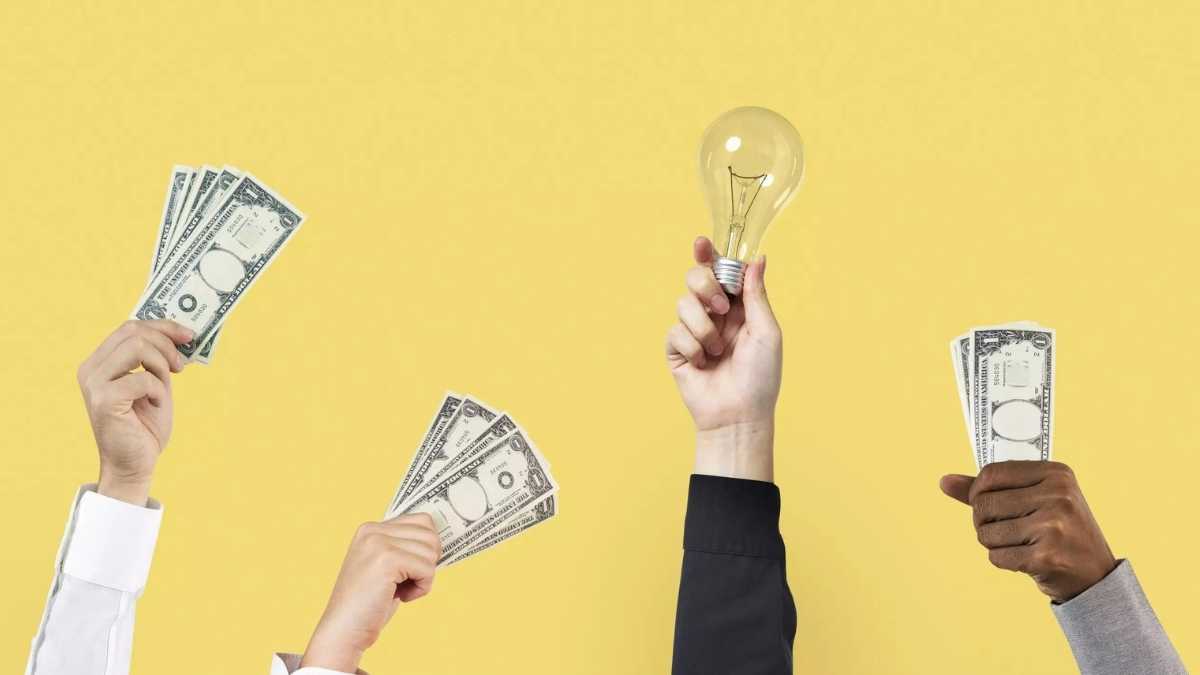 Quatro mãos para cima segurando notas de dinheiro e uma lâmpada - Startups