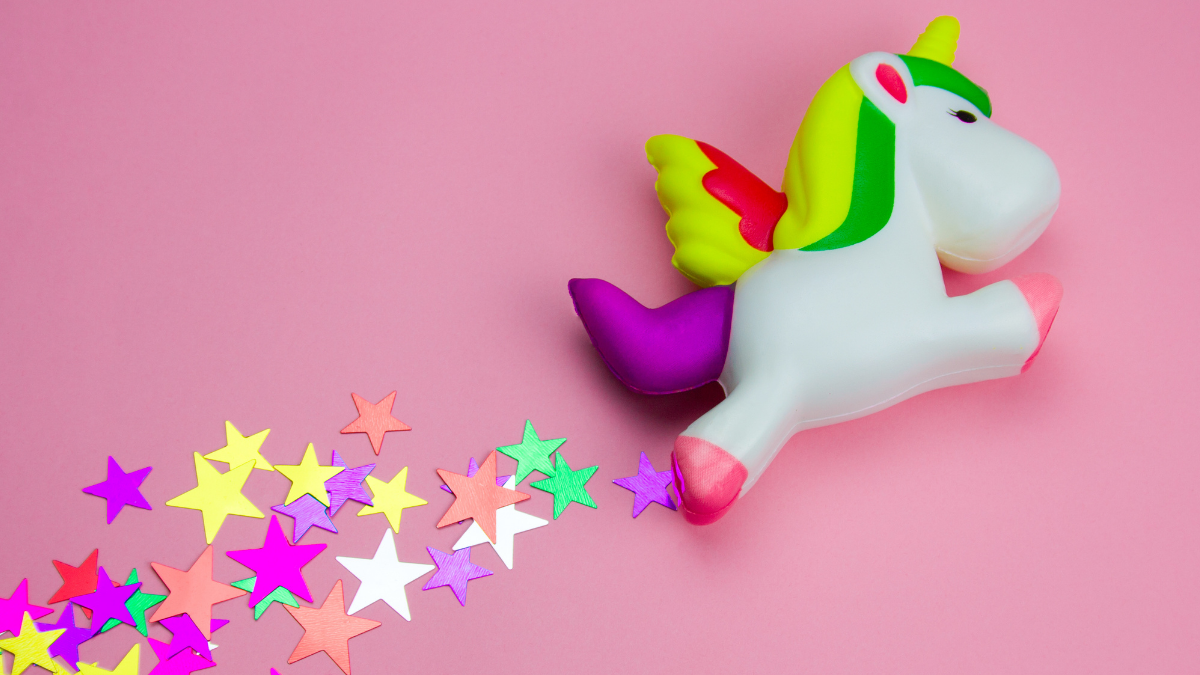 Unicórnio de brinquedo com estrelas coloridas em um fundo rosa - Startups